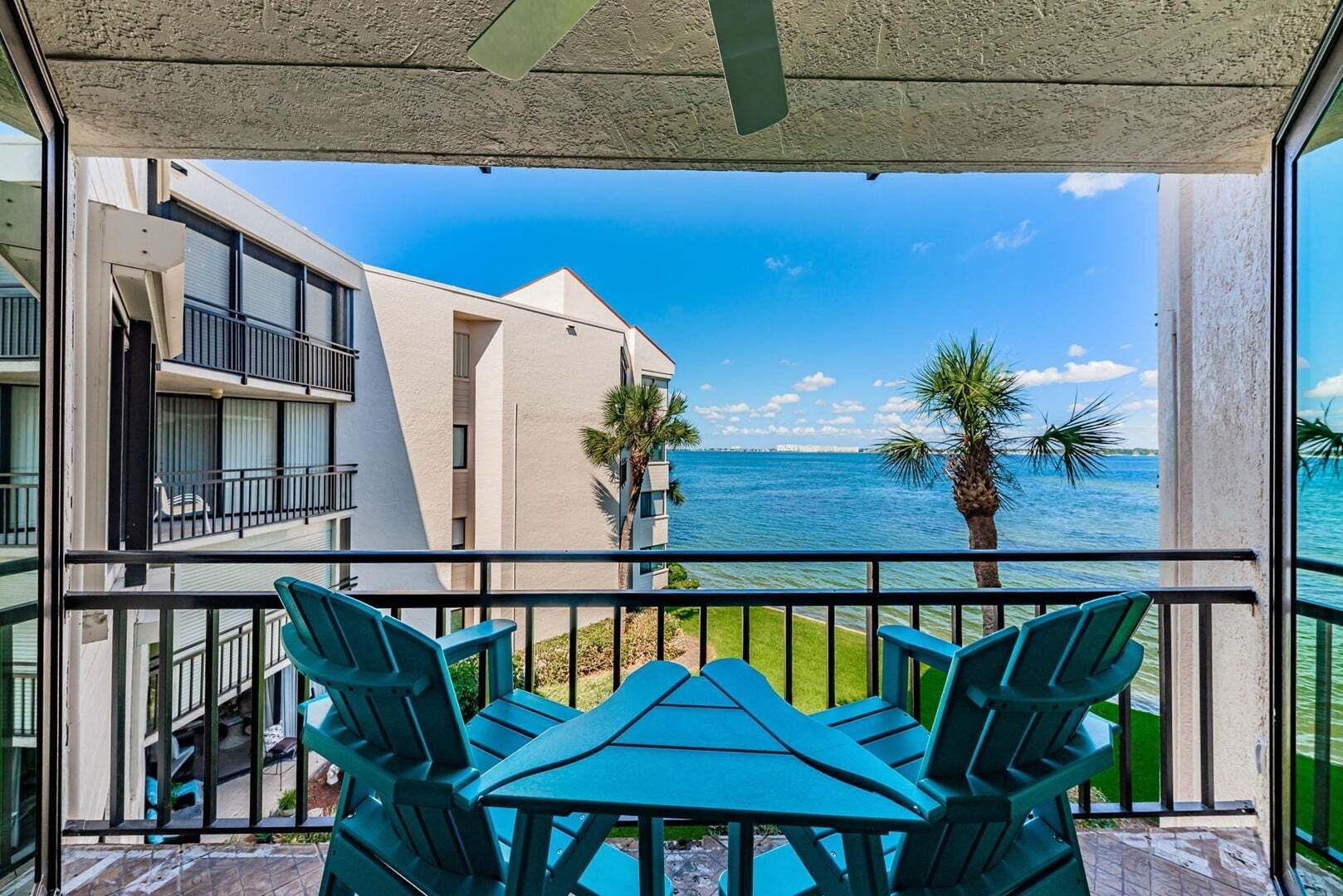 Un balcón con vistas al mar, una mesa con sillas y un edificio con balcones.