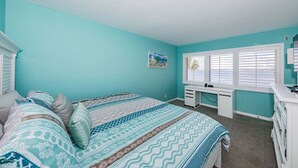 Une chambre avec deux lits, un bureau et une fenêtre avec des stores.