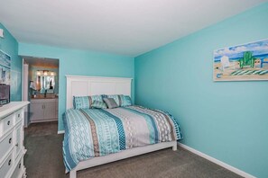 Ein Schlafzimmer mit Bett, Kommode und einem Bild an der Wand.