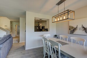 A modern kitchen with white cabinets, a dining area with a white table and chairs, and a staircase leading to another level. - Cozy 2 Bedroom King Beds/2 Bathroom Townhouse with Sunny Golf Views Sleeps 6 (Hilton Head)