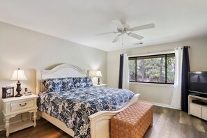A bedroom with a bed, bedside tables, a television, a ceiling fan, and a window with curtains. - 497 Captains Cove is a lovely property located close to the beach on HHI. (Hilton Head)
