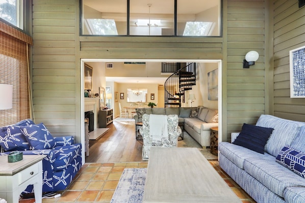 A spacious living room with a fireplace, a staircase, and a dining area.