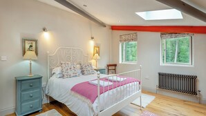 Ein Schlafzimmer mit Bett, Nachttischen, Fenster und Heizkörper.
