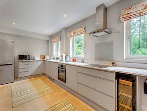 A modern kitchen with a built-in oven, microwave, and a large window with curtains.