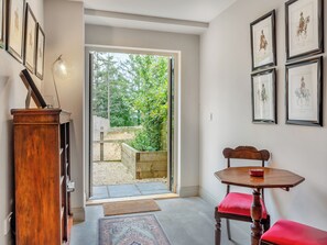 A room with a wooden bench, a small table, and framed artwork on the walls.