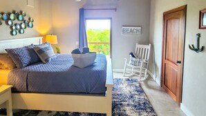 Een slaapkamer met een bed, een plafondventilator, een schommelstoel en een deur.
