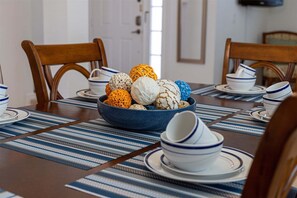 A dining table with a blue bowl filled with decorative items, surrounded by matching blue and white plates and bowls.