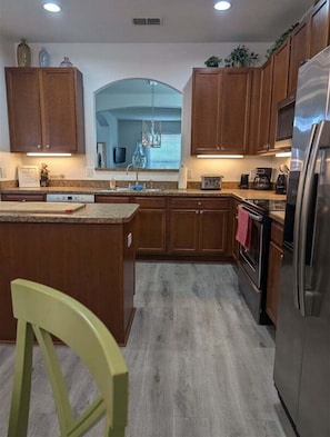 A kitchen with wooden cabinets, a stainless steel refrigerator, and a central island.