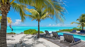 A beachside pool area with lounge chairs and a clear view of the ocean. - Ba Roos Beach House/Iconic Tar Bay Estate with 300’ of Direct Beachfront (Mosstown)