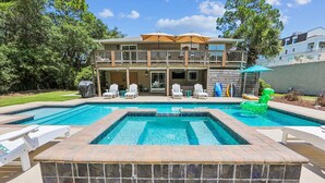 Uma casa de dois andares com piscina, área de estar externa e trampolim.