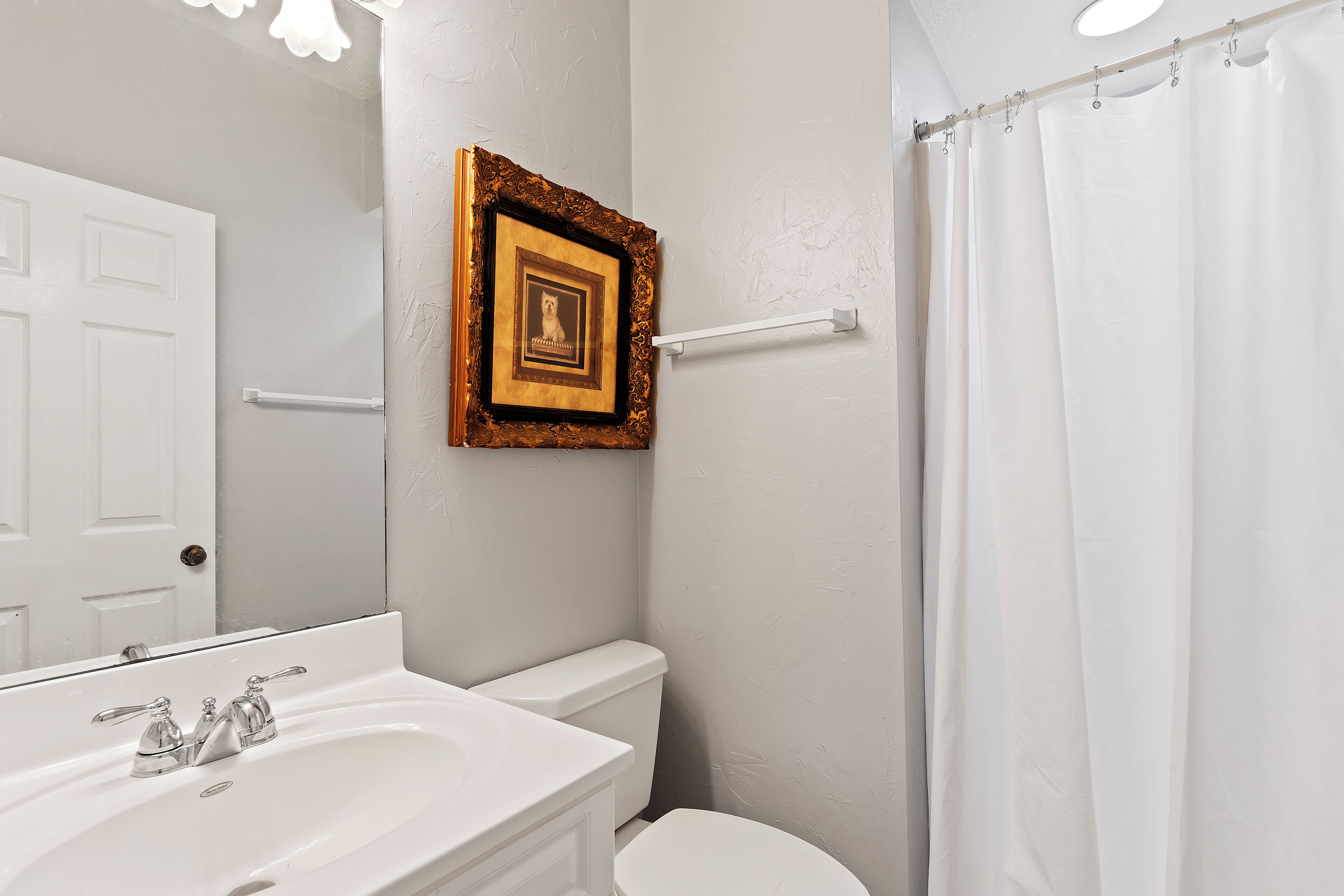 Un baño con lavamanos, inodoro y cortina de ducha blancos.