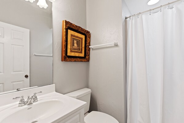 Une salle de bain avec un lavabo blanc, des toilettes et un rideau de douche.