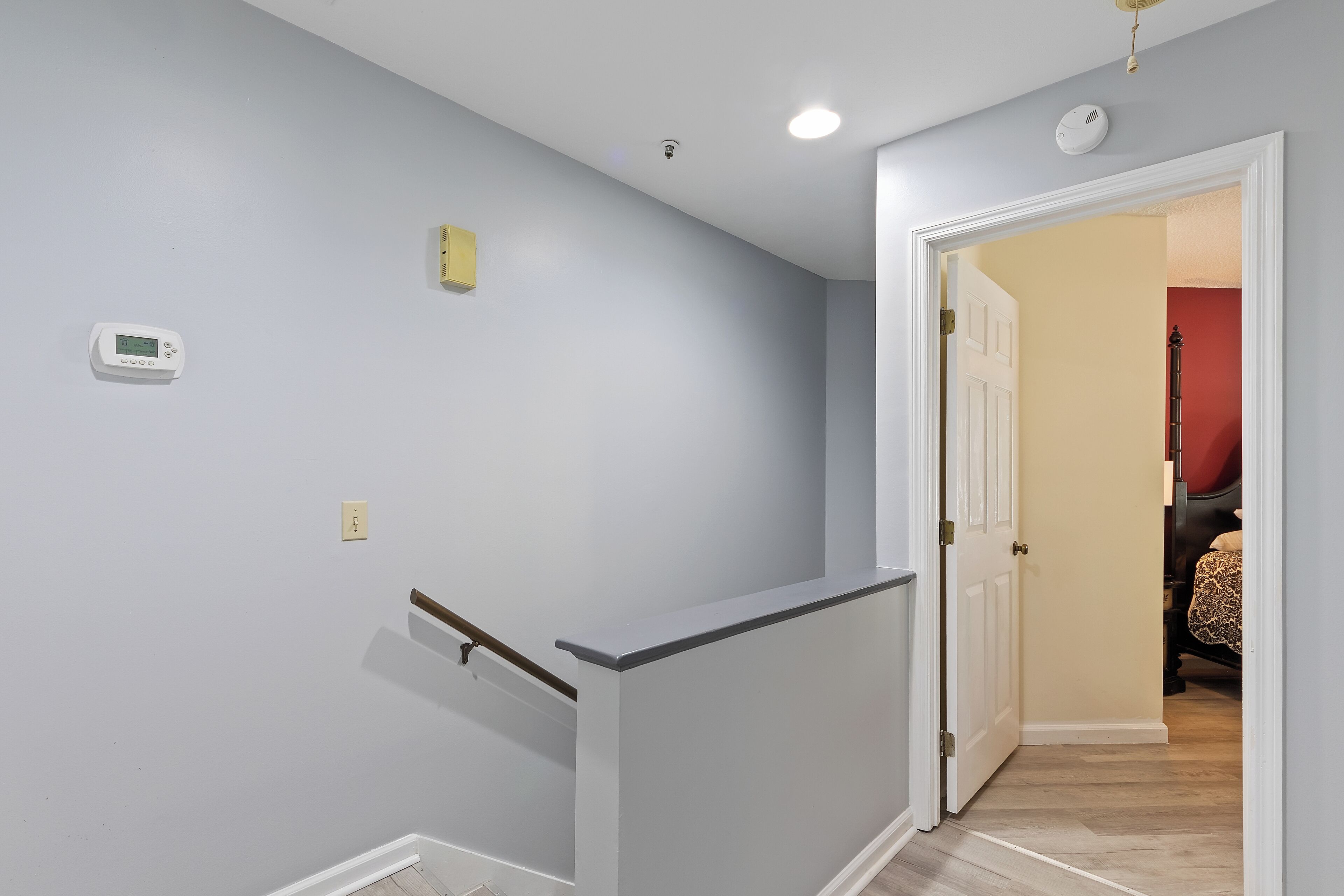 A hallway with a white door leading to a room with a red wall.