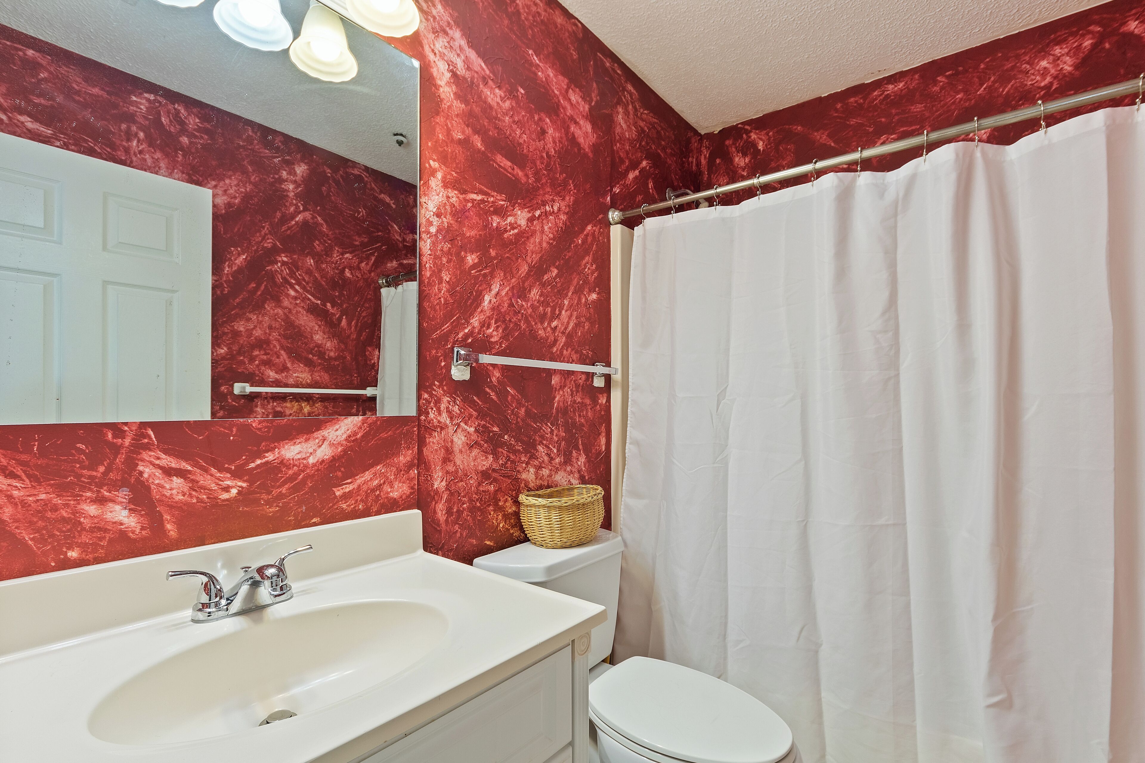 A bathroom with a white sink, a white toilet, and a shower curtain.
