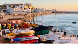 Un puerto deportivo con barcos amarrados, una playa y edificios al fondo.