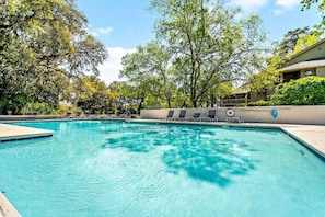 A swimming pool with lounge chairs and a building in the background. - Saint Andrews Common 1657 by Hilton Head Retreats (Hilton Head Island)