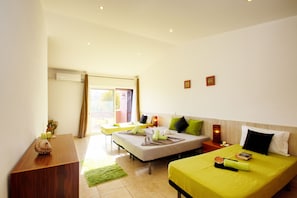 A hotel room with two beds, a wooden desk, a green rug, and a small table with a candle.