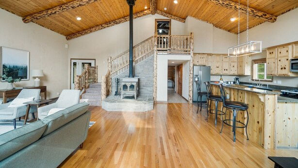 A spacious living area with a wooden ceiling, a stone fireplace, and a kitchen with wooden cabinets and a bar area. - Welcome to Lemon Lodge! Relax and unwind in this private and secluded cabin.  (Durango)