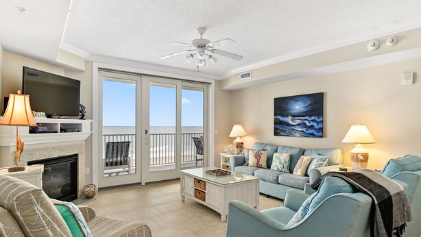 A living room with a TV, fireplace, and a balcony with a view.