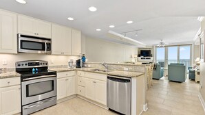 A modern kitchen with stainless steel appliances, a dishwasher, and a large island with seating.