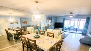 Un salon spacieux comprenant un coin repas, un téléviseur et un balcon.