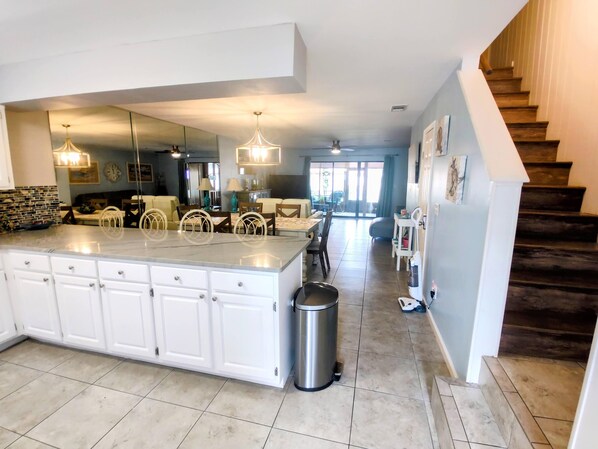 A spacious kitchen with a large island, white cabinetry, and a stainless steel trash can.