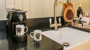 A kitchen with a coffee maker, a sink, and a wooden cutting board. - Moelfre - Shepherds Hut (Llanbedr)