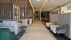 A modern hotel lobby with a central corridor, seating areas on both sides, and a reception desk. - Holiday Inn Express Monterrey Fundidora by IHG (Monterrey)
