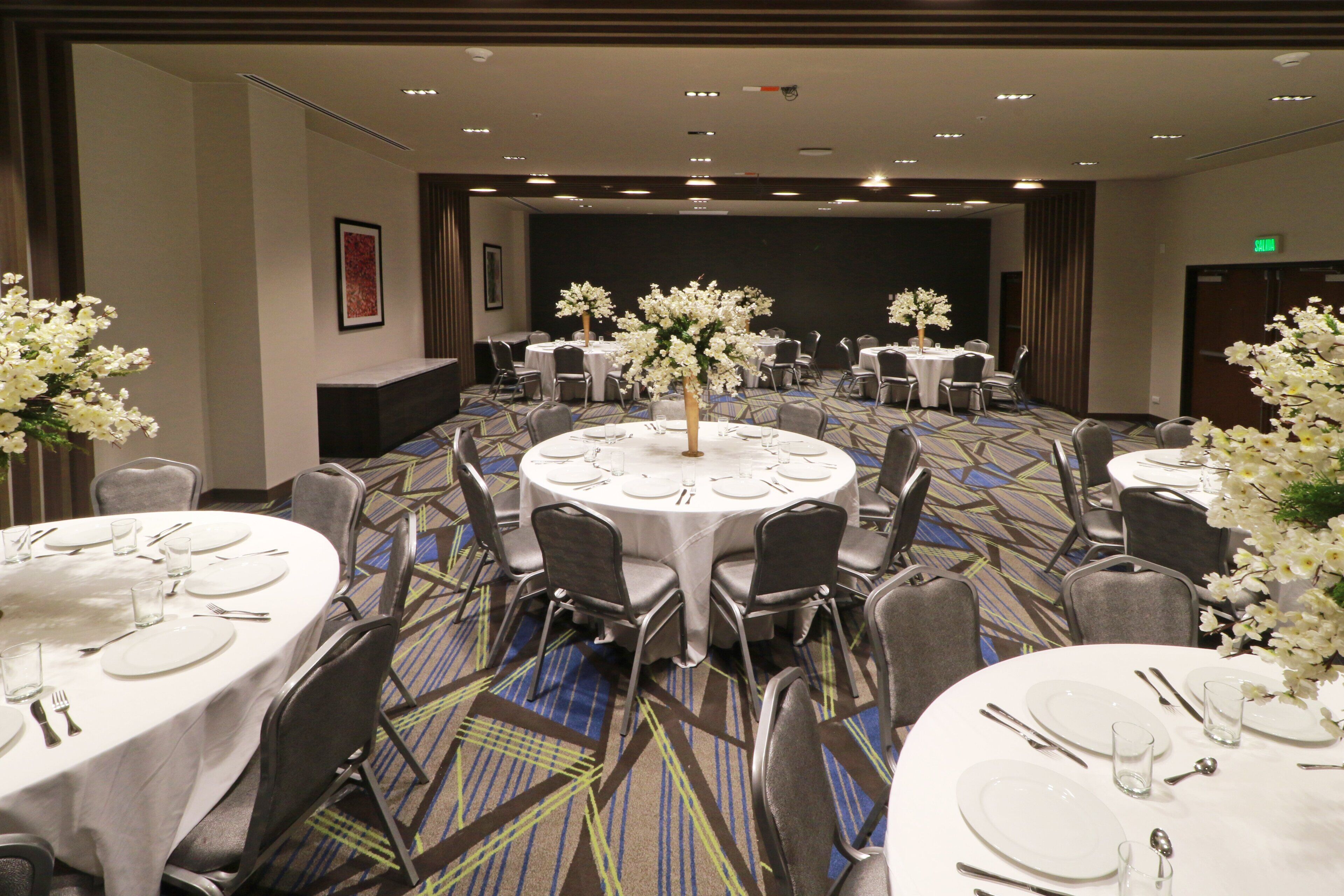 A conference room with round tables, chairs, and floral centerpieces.