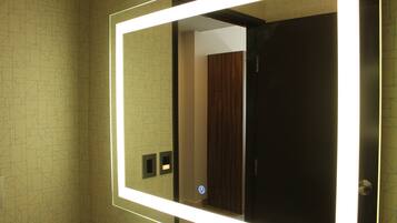 A bathroom with a mirror, a wooden door, and a patterned wall.