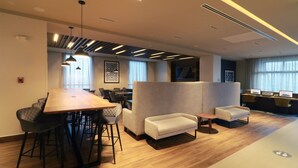 A modern office space with a long wooden table, several chairs, a sofa, and a small table. - Holiday Inn Express Monterrey Fundidora by IHG (Monterrey)