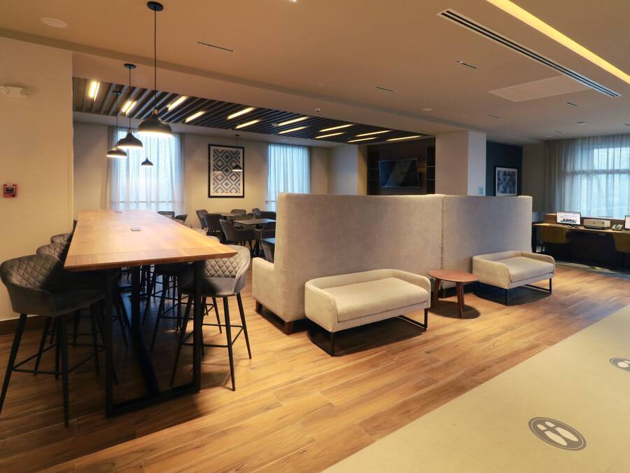 Un espacio de oficina moderno con una mesa de madera larga, varias sillas, un sofá y una pequeña mesa.