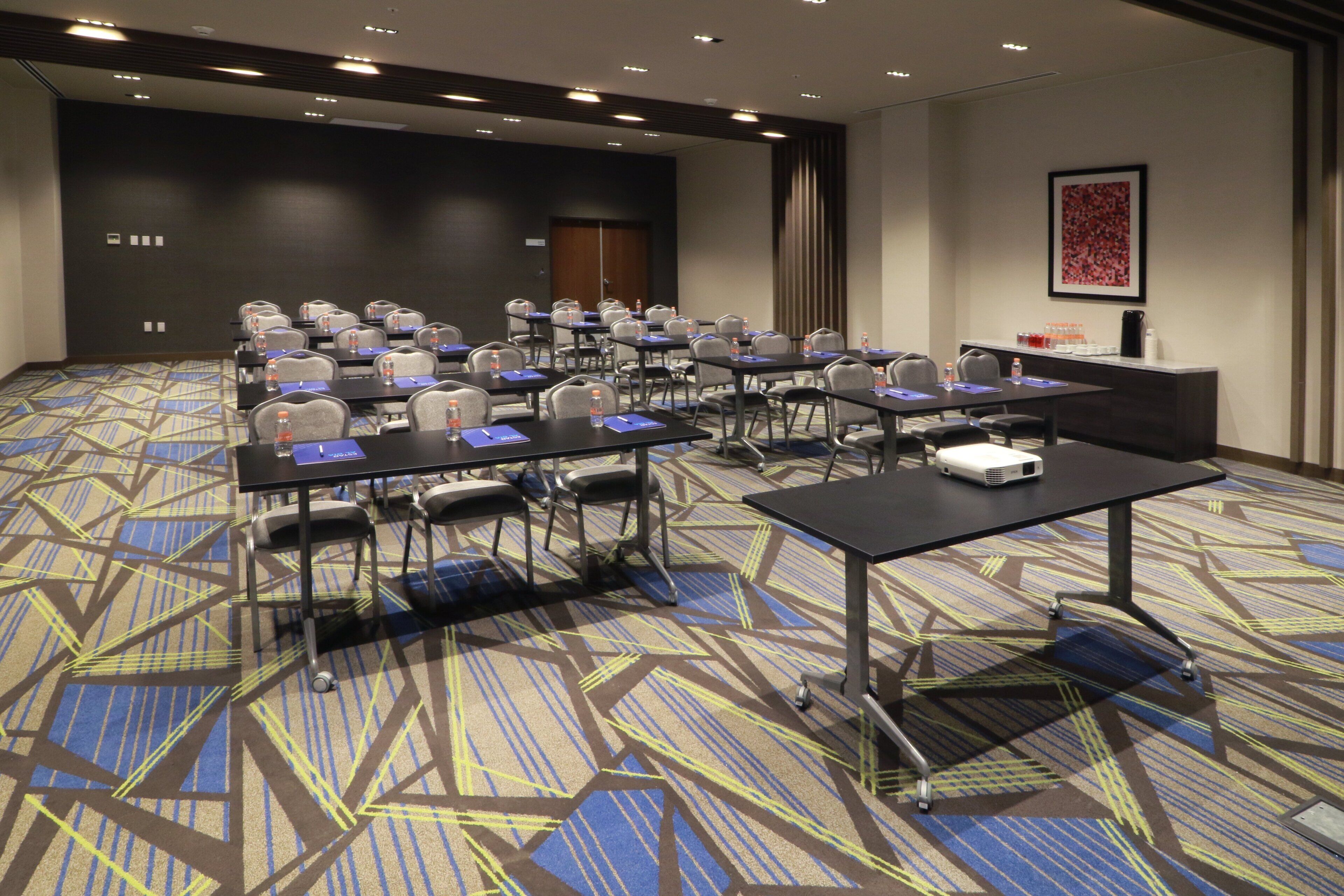 A conference room with multiple tables and chairs, equipped with water bottles and nameplates.