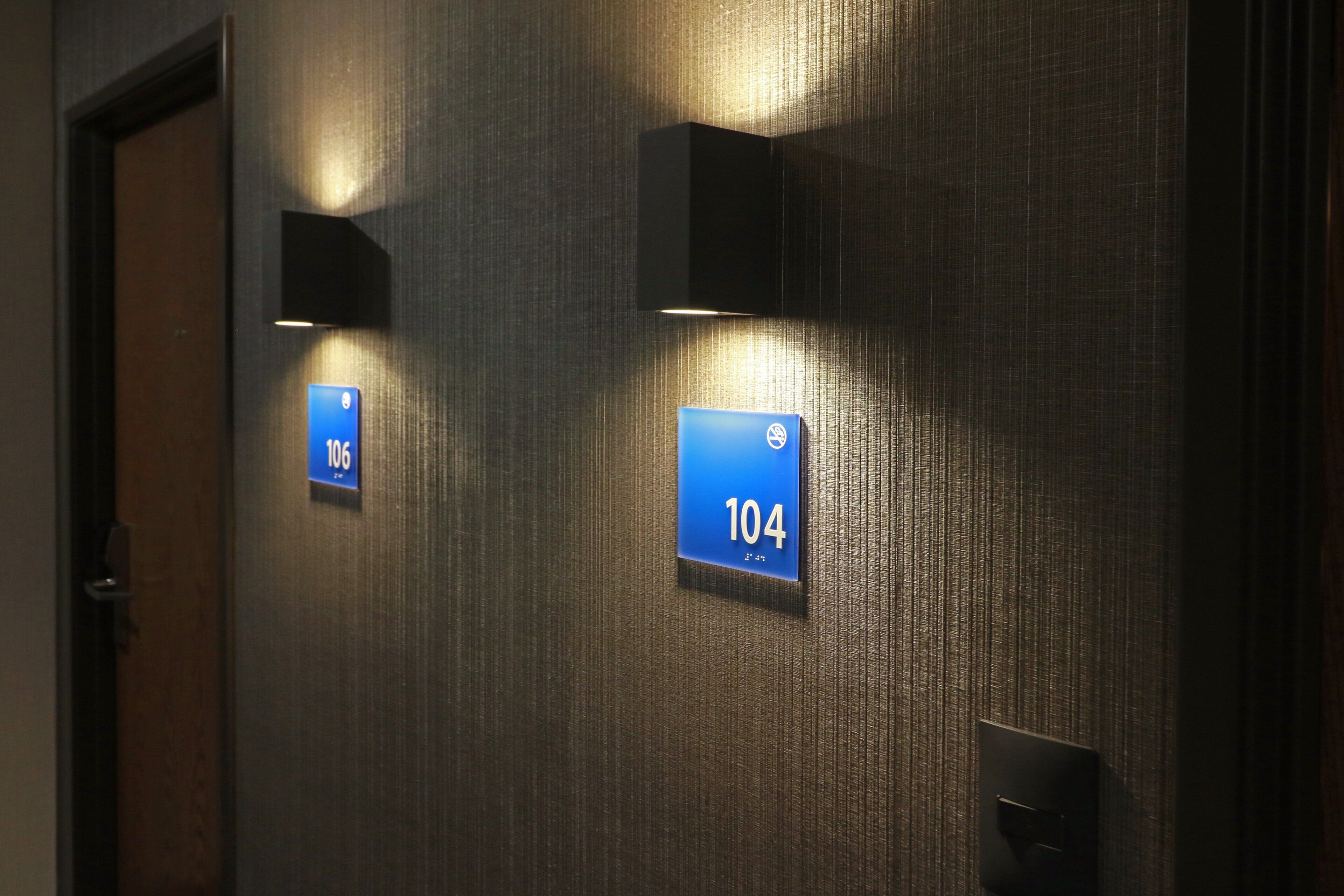 A wall with two illuminated signs indicating room numbers 106 and 104.