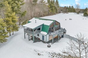 A cabin with a green roof, a balcony, and a covered porch area.