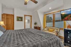 Ein Schlafzimmer mit einem großen Bett, einem Holzkartonventilator, einem Fernseher, einem Sofa und einer Kommode.