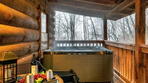 A wooden cabin interior with a hot tub, a bottle of wine, and a tray of fruit. - Fall Colors! Large Hot Tub, Private, Easy Access (Sevierville)