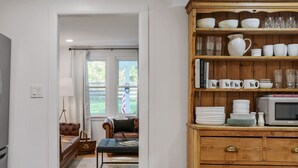 A kitchen with wooden cabinets, a microwave, and a dining area with a sofa and table.
