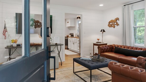 A modern living room with a leather sofa, a coffee table, and a dining area with a table and chairs.