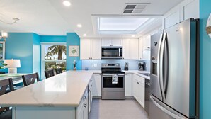 A modern kitchen with white cabinets, stainless steel appliances, and a skylight. - Beautiful bright, updated 2 bedroom, 2 bath oceanfront condo spectacular views! (Stuart)