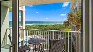 A balcony with a view of the ocean, a pool, and a dining area with wicker furniture. - Beautiful bright, updated 2 bedroom, 2 bath oceanfront condo spectacular views! (Stuart)