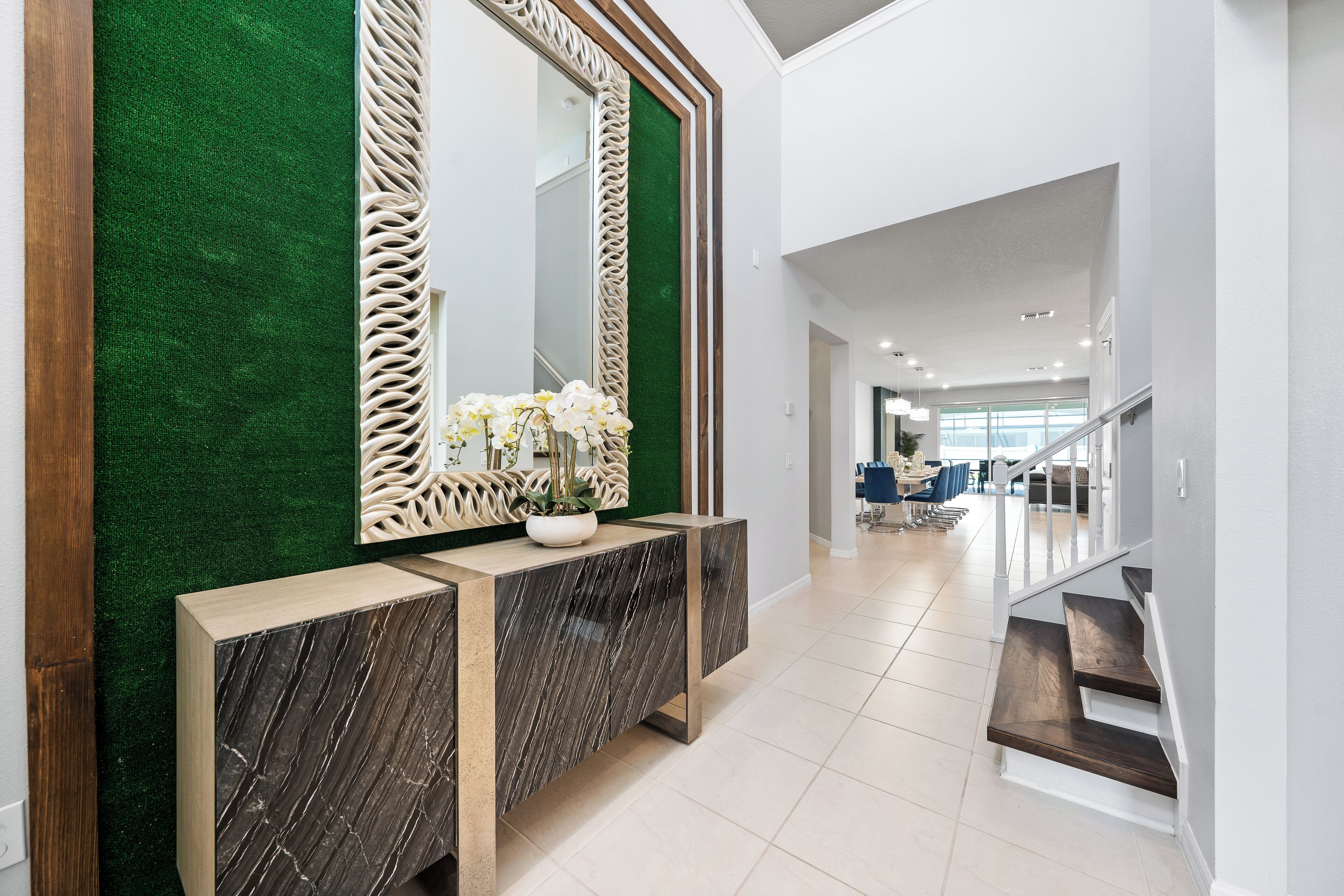 A modern interior with a green wall, a marble console, and a large mirror.