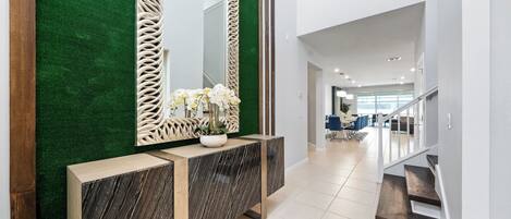 A modern interior with a green wall, a marble console, and a large mirror.