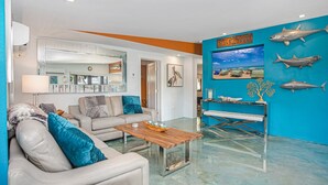 A modern living room with a sofa, coffee table, and a wall decorated with fish and a painting.