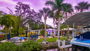 A resort with a pool, palm trees, and a boat dock.