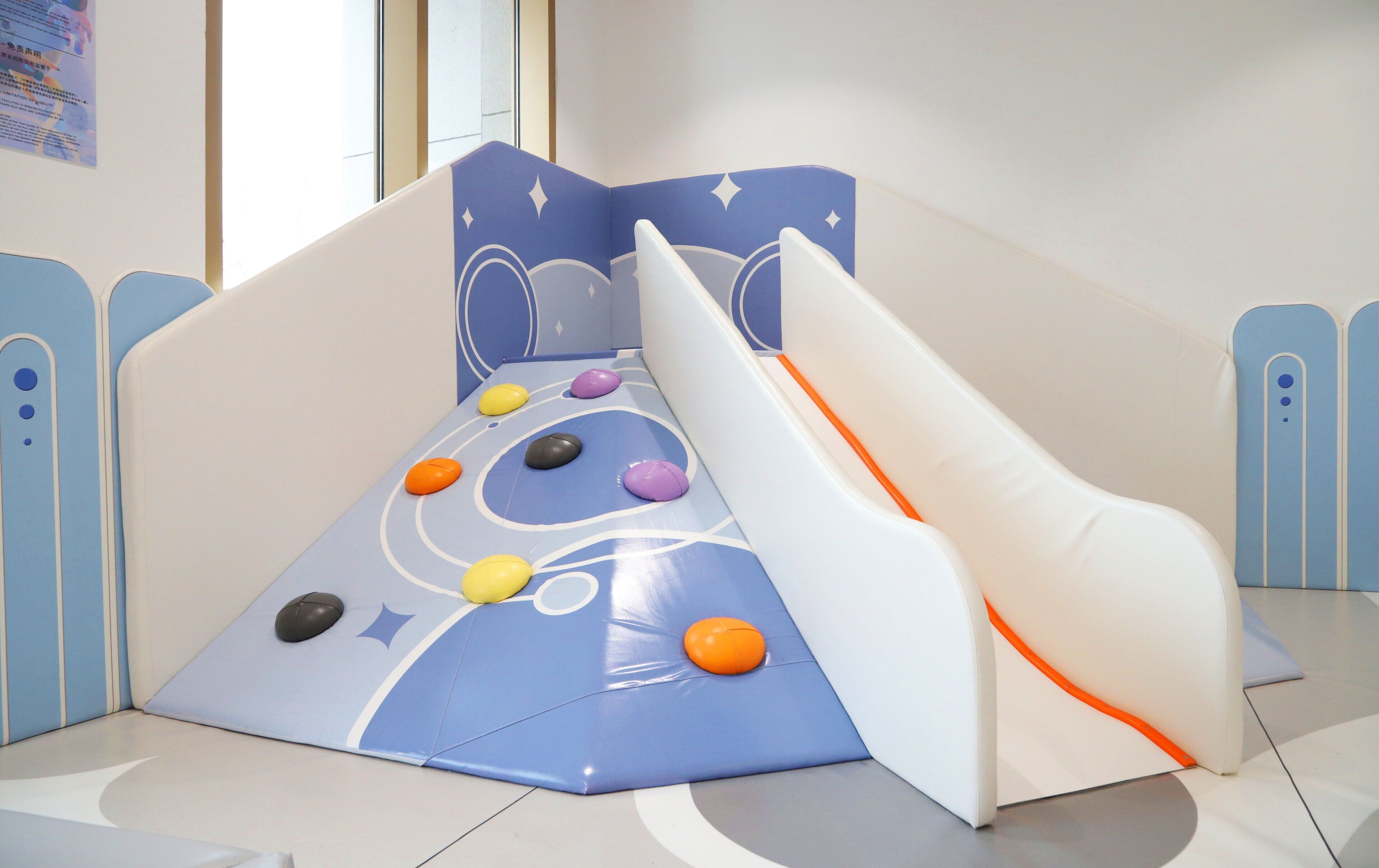 Zona infantil con tobogán y pared de escalar.