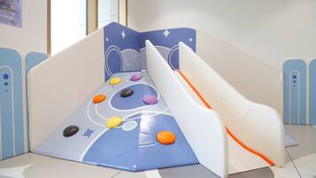 Zona infantil con tobogán y pared de escalar.