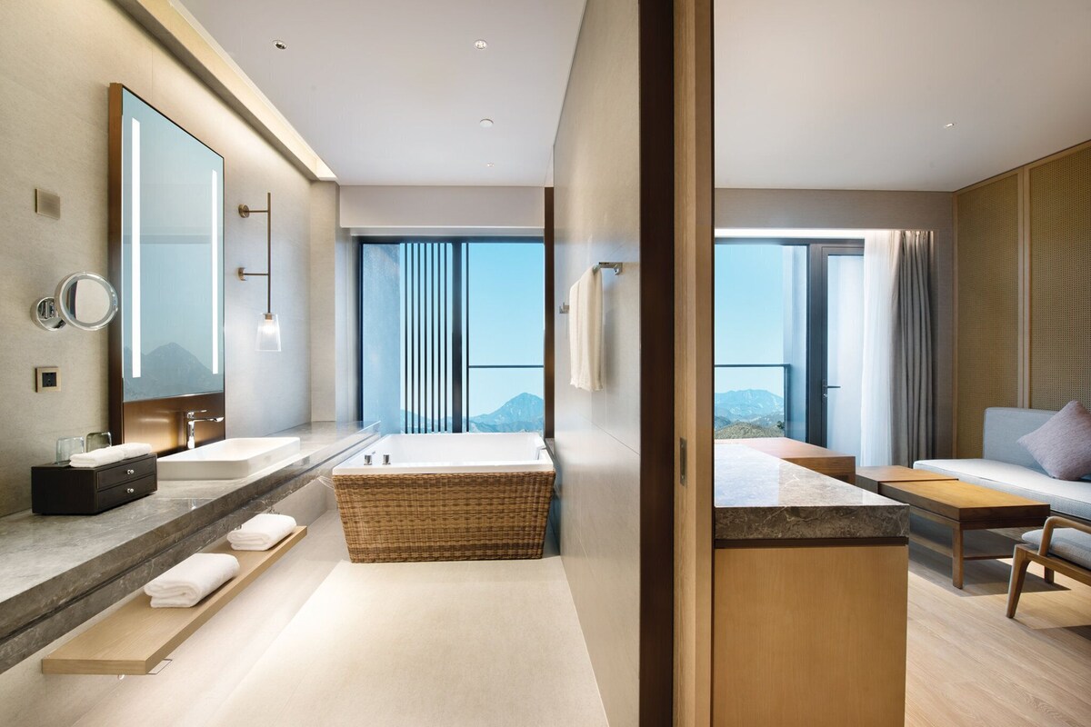A modern bathroom with a large bathtub, a double sink, and a vanity with a mirror.