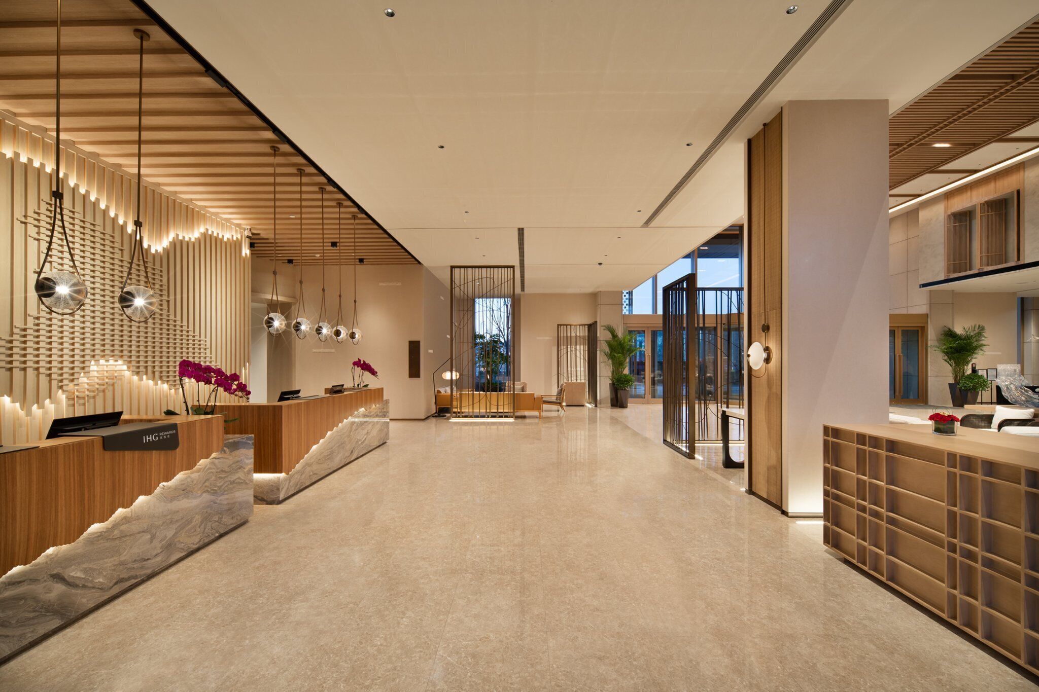 A modern hotel lobby with a reception desk, seating area, and large windows.