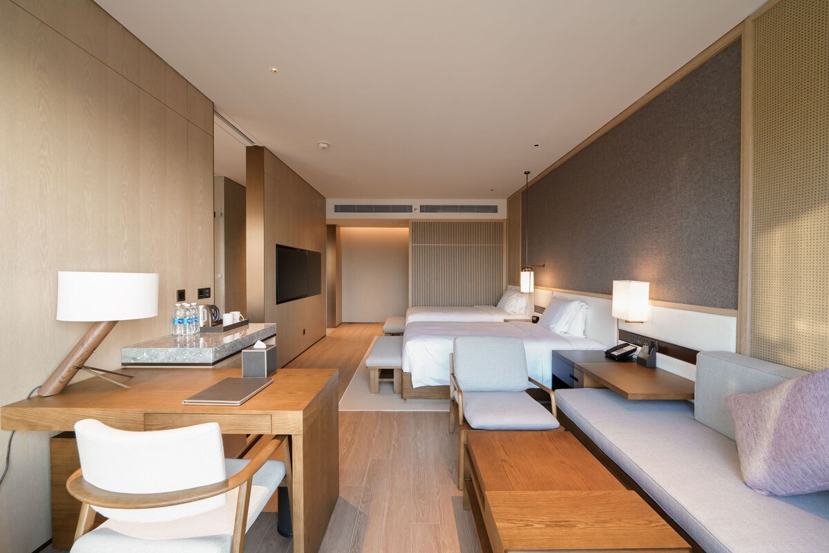 Een moderne hotelkamer met een houten bureau, een bank, een bed en een televisie.